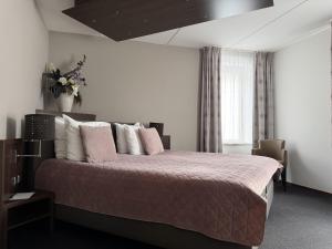 a bedroom with a large bed with pink and white pillows at Hampshire Hotel - Avenarius in Ruurlo +33 photos