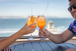 two people holding up glasses of orange juice at Hermanus Waterfront Apartments in Hermanus