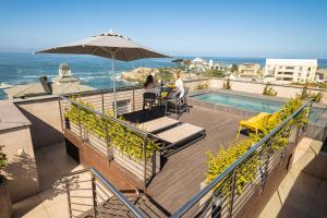 a man and woman sitting on a balcony with an umbrella at Hermanus Waterfront Apartments in Hermanus