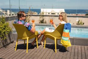 a man and woman sitting in chairs drinking wine at Hermanus Waterfront Apartments in Hermanus