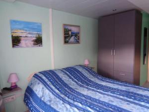 a bedroom with a bed with a blue comforter at Apartment Philippeville 18 m² Garden in Philippeville
