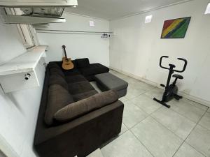 a living room with a brown couch and a guitar at Le coin des romarins in Saint-André