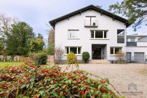 a white house with a lot of red flowers at La VILLA du Reims - Mon Gîte Facile in Colmar