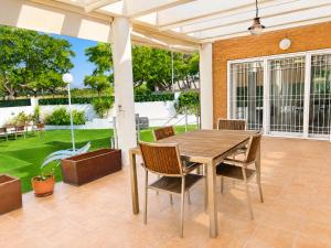 an outdoor patio with a wooden table and chairs at Villa La Perla - Pool, Garden & Barbecue - AC in Mutxamel
