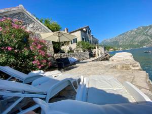a group of chairs and an umbrella next to the water at House with a pier in Donji Morinj