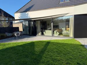 a glass extension of a house with a lawn at Ferienwohnung Zwischenzeit in Kranenburg