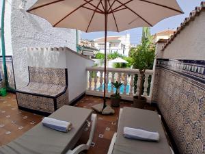 a balcony with two chairs and an umbrella at Casa Lunamar in Rincón de la Victoria