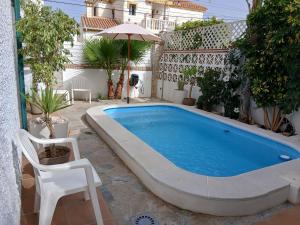 a pool in the middle of a yard with a chair and an umbrella at Casa Lunamar in Rincón de la Victoria