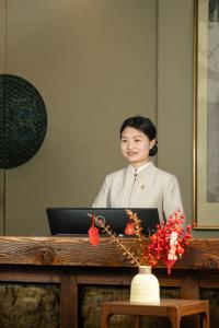 a woman sitting at a desk with a laptop computer at Garden Hotel Suzhou in Suzhou