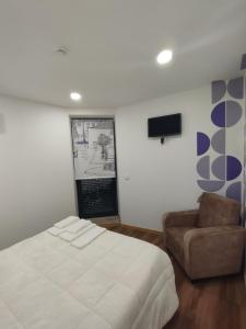 a bedroom with a bed and a chair and a tv at SeiaVilla - 4 Fontes in Seia