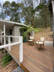 a wooden deck with two chairs and a house at Noojee views - cozy studio in Noojee