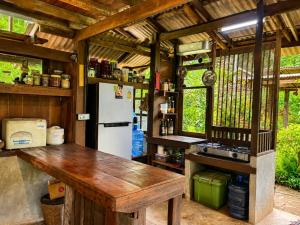 a kitchen with a wooden table and a refrigerator at Indigo Homestay in Ban Huai Pong