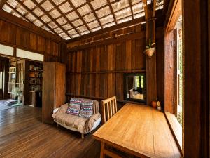 a wooden room with a table and a couch at Indigo Homestay in Ban Huai Pong