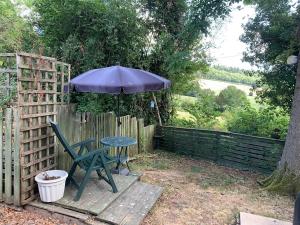 a table with an umbrella next to a fence at Hedgehog Lodge in Colwall +60 photos