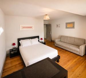 a bedroom with a white bed and a couch at Guest House Vimaranes in Guimarães