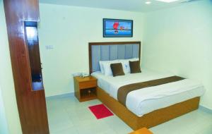 a bedroom with a large bed and a night stand at Hotel Crown City in Chittagong