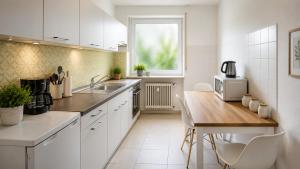 a kitchen with white cabinets and a wooden table at Pulheim Living 3 in Pulheim