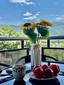 a vase with flowers on a table with a plate of fruit at Tatev& Alex BnB in Tatʼev