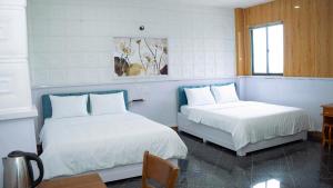 a bedroom with two beds and a table and a window at Solar Tower in Soc Trang