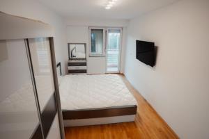 a white bedroom with a bed and a television at The Red Lounge in Strumica