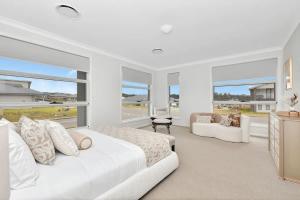 a white bedroom with a large bed and windows at Hunter Valley Bercuti in North Rothbury
