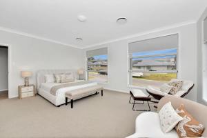 a white bedroom with a bed and a couch at Hunter Valley Bercuti in North Rothbury