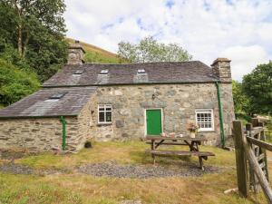 an old stone cottage with a picnic table in front of it at Frondirion in Machynlleth