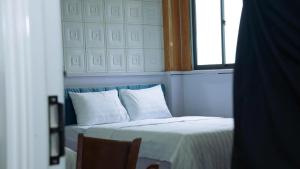 a bedroom with a bed with white pillows and a window at Solar Tower in Soc Trang
