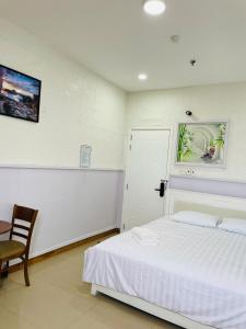 a bedroom with a white bed and a table and chair at Solar Tower in Soc Trang