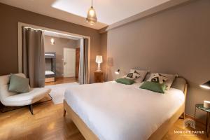 a bedroom with a large white bed and a chair at La VILLA du Reims - Mon Gîte Facile in Colmar