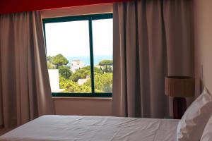 a bedroom with a bed and a large window at Balaia Plaza in Albufeira