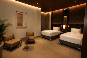 a hotel room with two beds and a chair at Ananta Express Jaunpur in Jaunpur