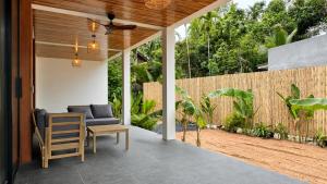 an outdoor patio with a couch and a chair at Maprao Tropical Home in Ko Phangan
