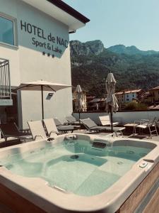 a hot tub with chairs and umbrellas in front of a hotel at Hotel De Nac in Nago-Torbole