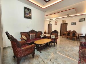 a living room with couches and a table and chairs at Rayta Aravalli View Villa in Udaipur