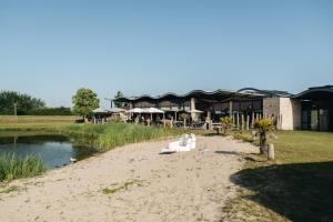 a beach in front of a building next to a body of water at Resort Land & Zee in Scharendijke