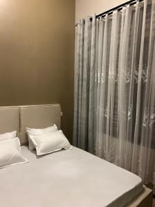 a bed with two pillows in front of a curtain at Vn mbeya apartment in Mbeya