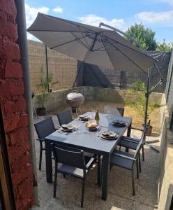 a table with chairs and an umbrella on a patio at gîte 6 personnes le cocon des pommes in Saint-Lambert-et-Mont-de-Jeux