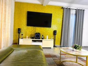 a living room with a couch and a tv on a yellow wall at Immeuble paco in Douala