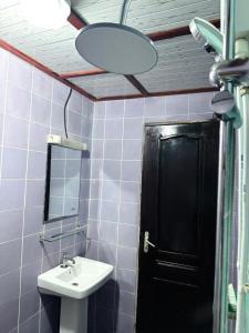 a bathroom with a sink and a black door at Immeuble paco in Douala +7 photos