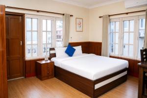 a bedroom with a bed and two windows at Suva Garden Hotel in Kathmandu