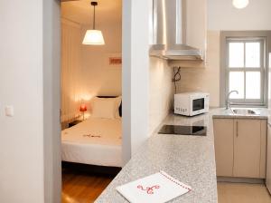 a small room with a bed and a kitchen at Guest House Vimaranes in Guimarães