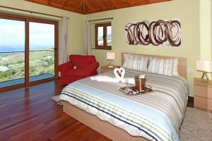 a bedroom with a large bed and a red chair at Casa Vista Mar in Tijarafe +12 photos
