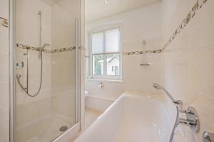 a white bathroom with a tub and a shower at Ferienhaus Oscar in Garz +26 photos