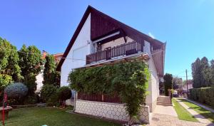 a building with a balcony and ivy on it at Oli vendégház in Balatonboglár