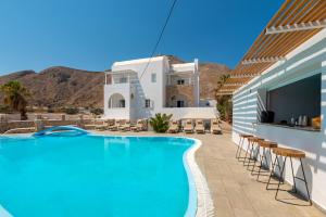 a swimming pool with chairs and a building at Noème Santorini in Perissa