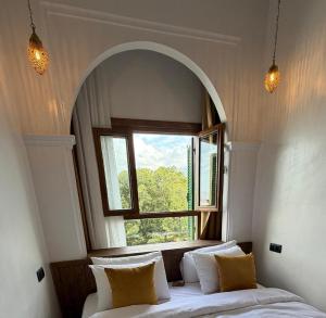 a bedroom with a window and a bed with pillows at Riad los simbolos in Tétouan
