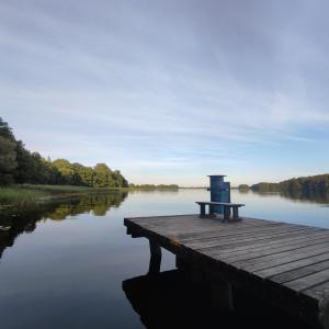 a bench sitting on a dock on a lake at Nowoczesny jasny apartament nad Jeziorem in Szczecinek