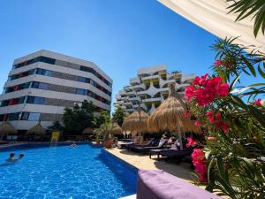 a swimming pool with chairs and a building at Ella Luxury Apartament in Năvodari