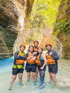 a group of people in the water in front of a waterfall at CocoVille Guesthouse KUBO in Alegria